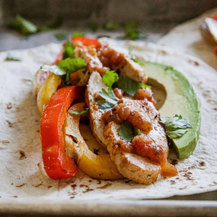 Delicious chicken fajitas with peppers and avocado on a soft tortilla.