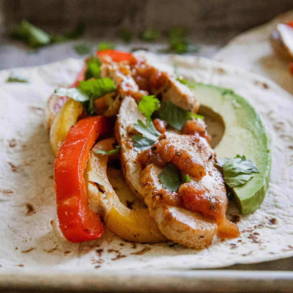 Delicious chicken fajitas with peppers and avocado on a soft tortilla.