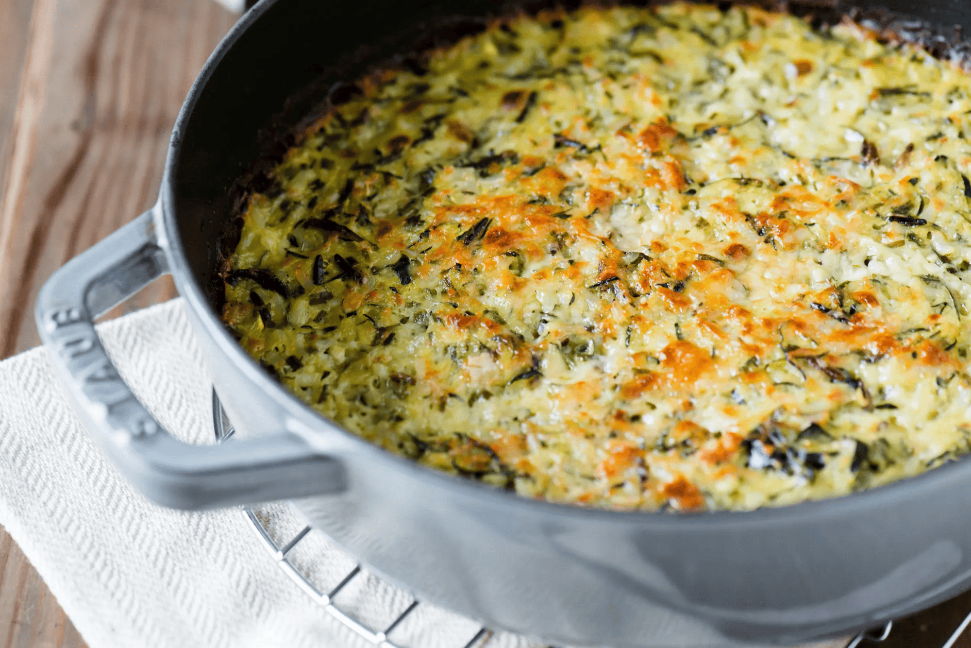 Baked wild rice casserole with cheese and herbs in a black skillet.