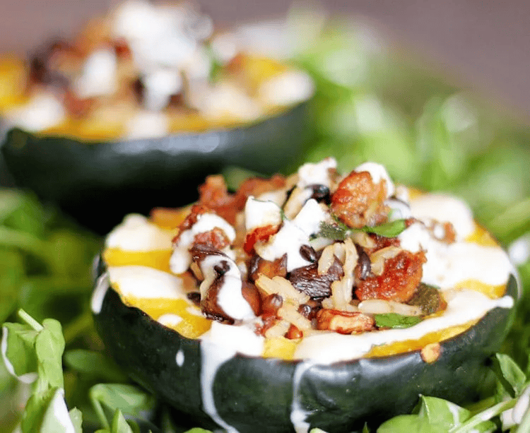 Stuffed acorn squash filled with wild rice, vegetables, and cheese, served on a bed of greens.