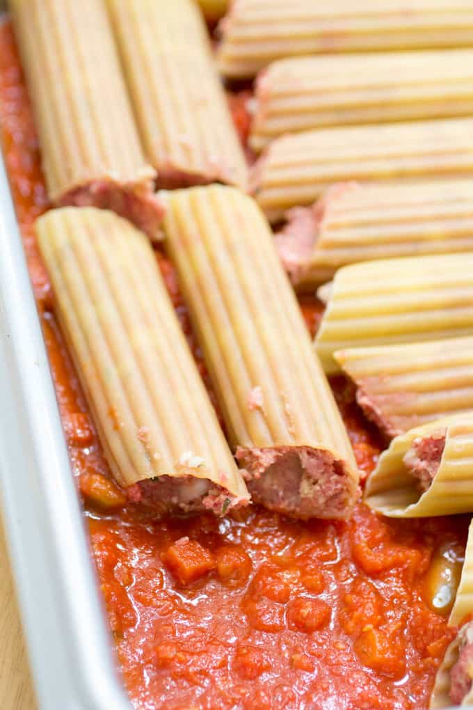 Place the stuffed manicotti into a baking pan that's been covered in sauce.