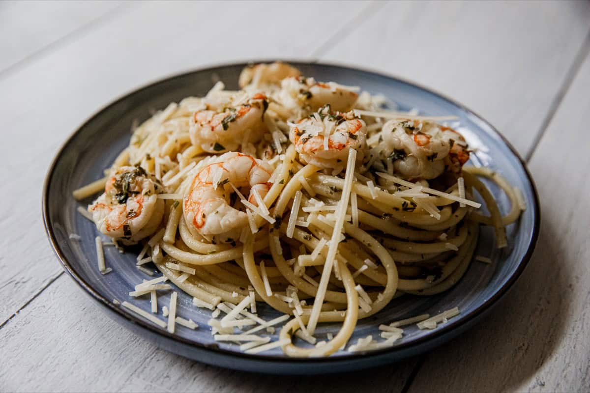 Delicious shrimp scampi pasta with grated cheese on a dark plate.