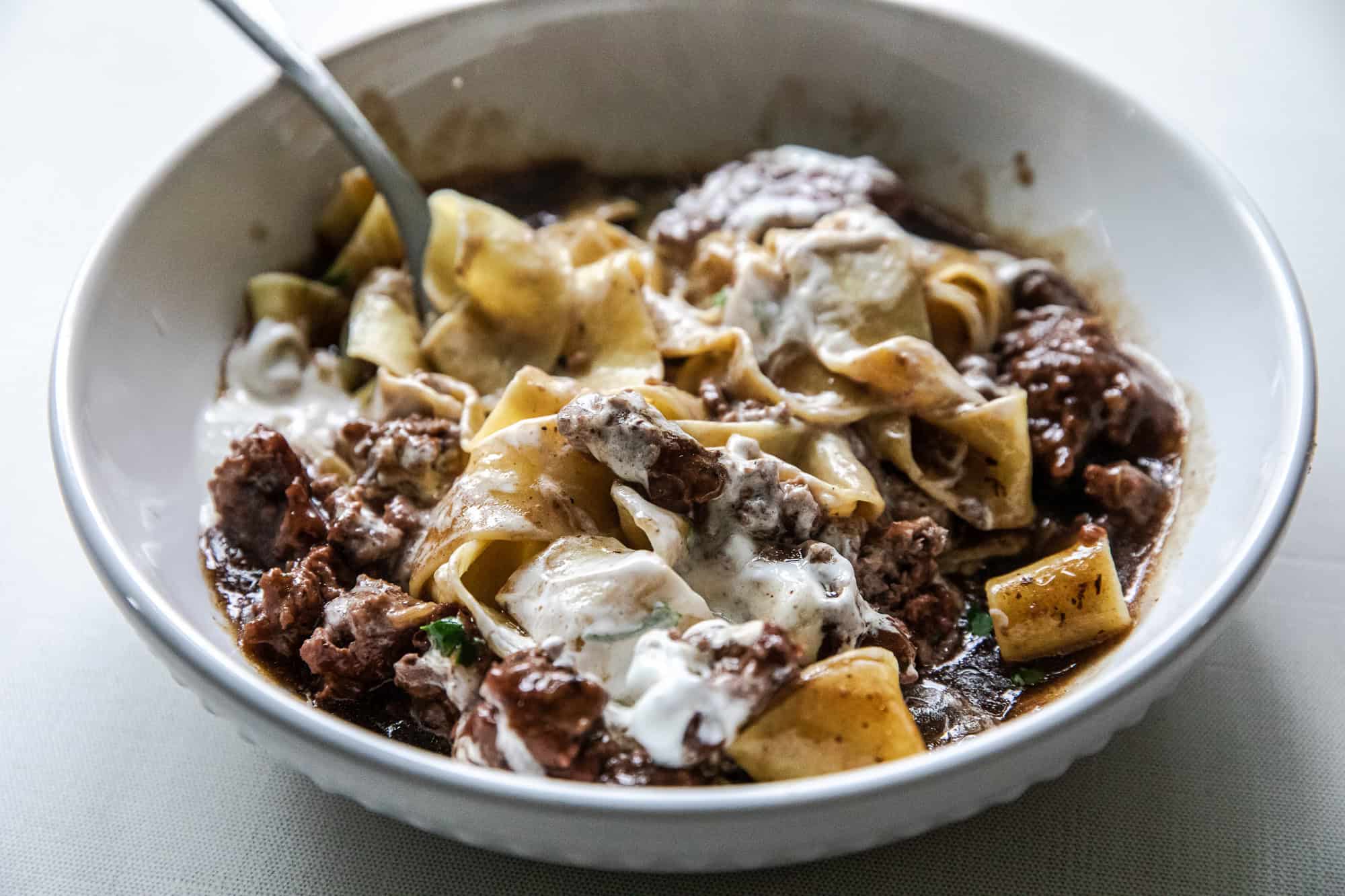 Delicious ground beef stroganoff with noodles and creamy sauce in a white bowl.