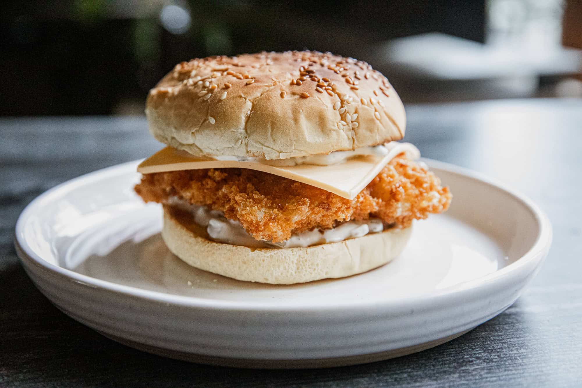 Crispy panko breaded fish fillet in sandwich with cheese on bun.