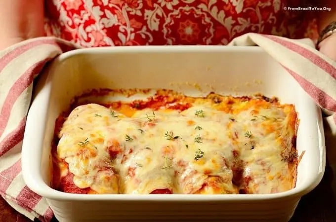 Baked Chicken Parm in a casserole dish held with potholders in hands