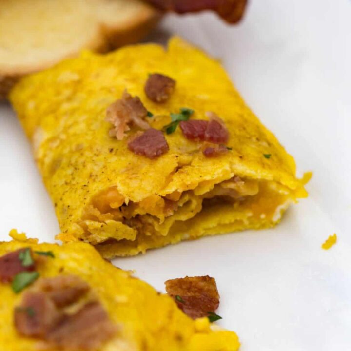 Delicious bacon cheese omelet cooked on a Blackstone griddle with fluffy eggs and melted cheese.