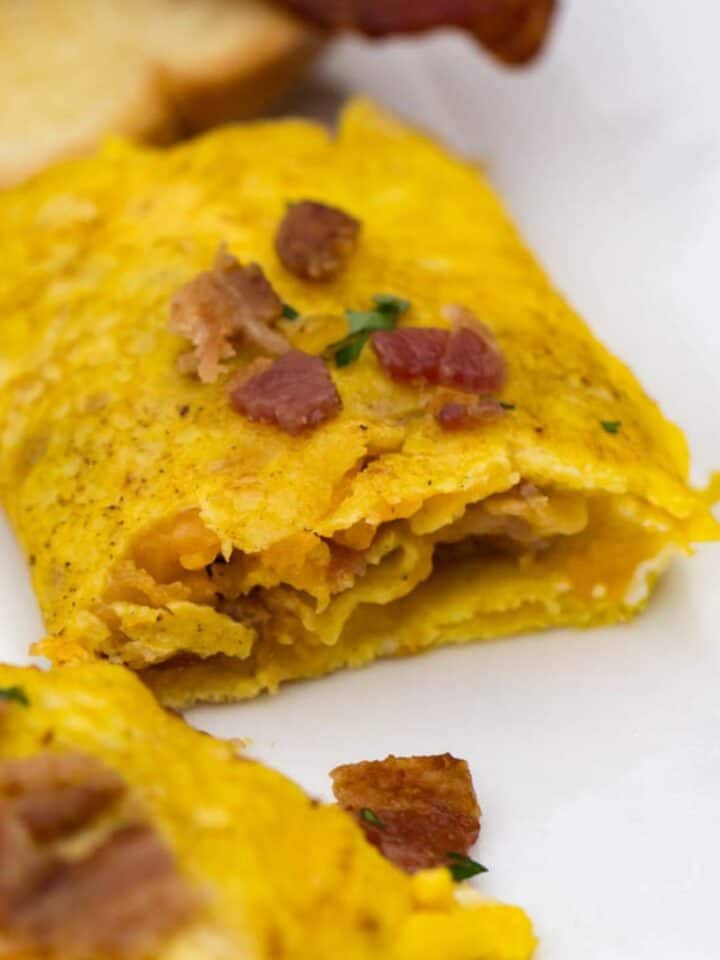 Delicious bacon cheese omelet cooked on a Blackstone griddle with fluffy eggs and melted cheese.