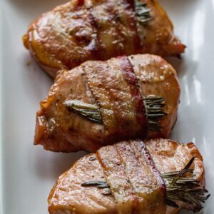 Delicious bacon-wrapped pork chops grilled to perfection with fresh rosemary for added flavor.