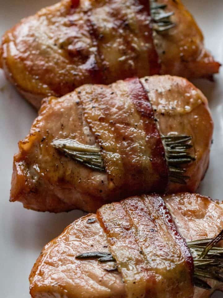 Delicious bacon-wrapped pork chops grilled to perfection with fresh rosemary for added flavor.