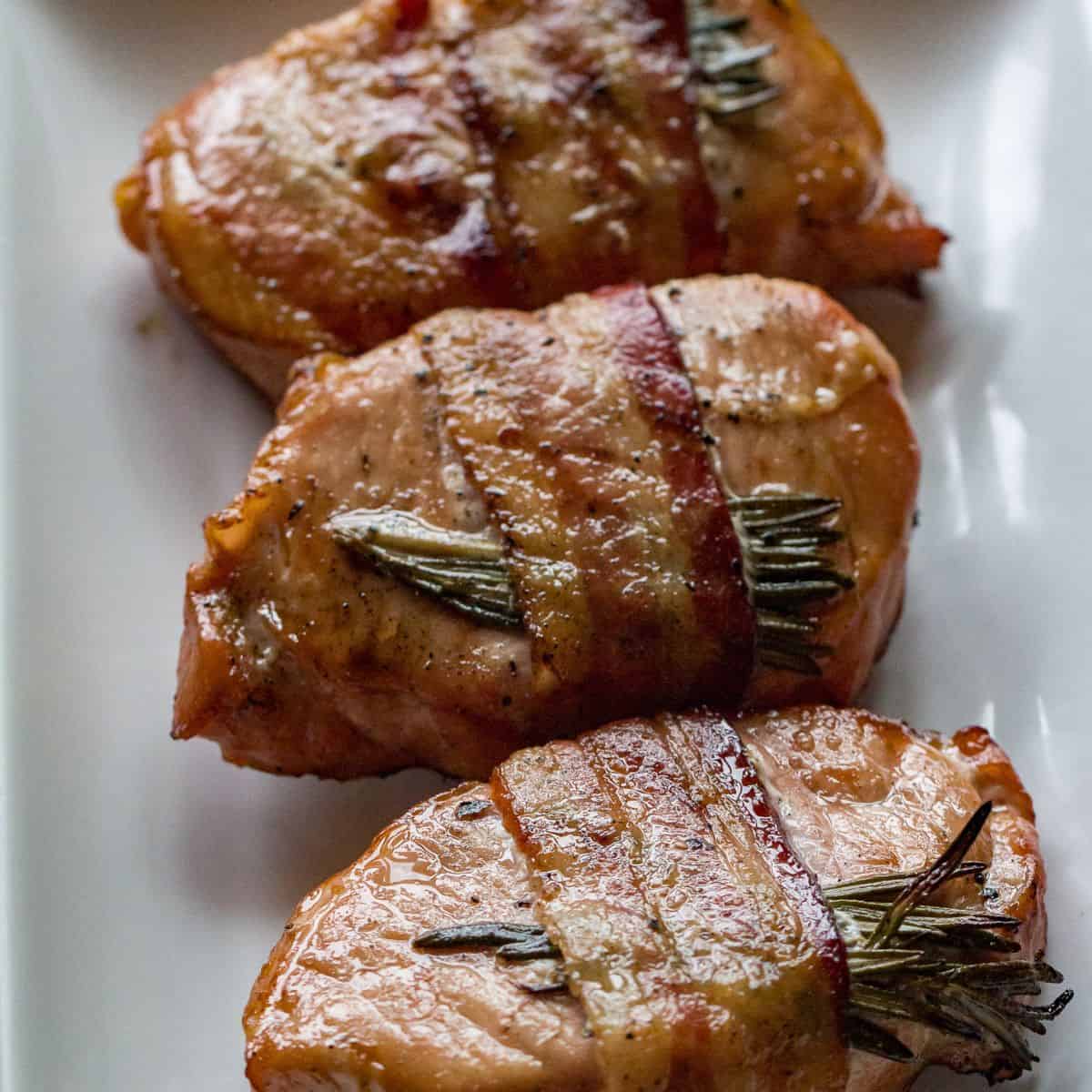 Delicious bacon-wrapped pork chops grilled to perfection with fresh rosemary for added flavor.