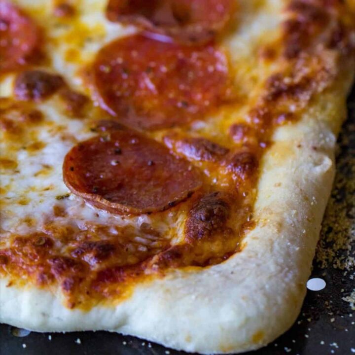 Close-up of pepperoni pizza slice baked in a pizza oven.