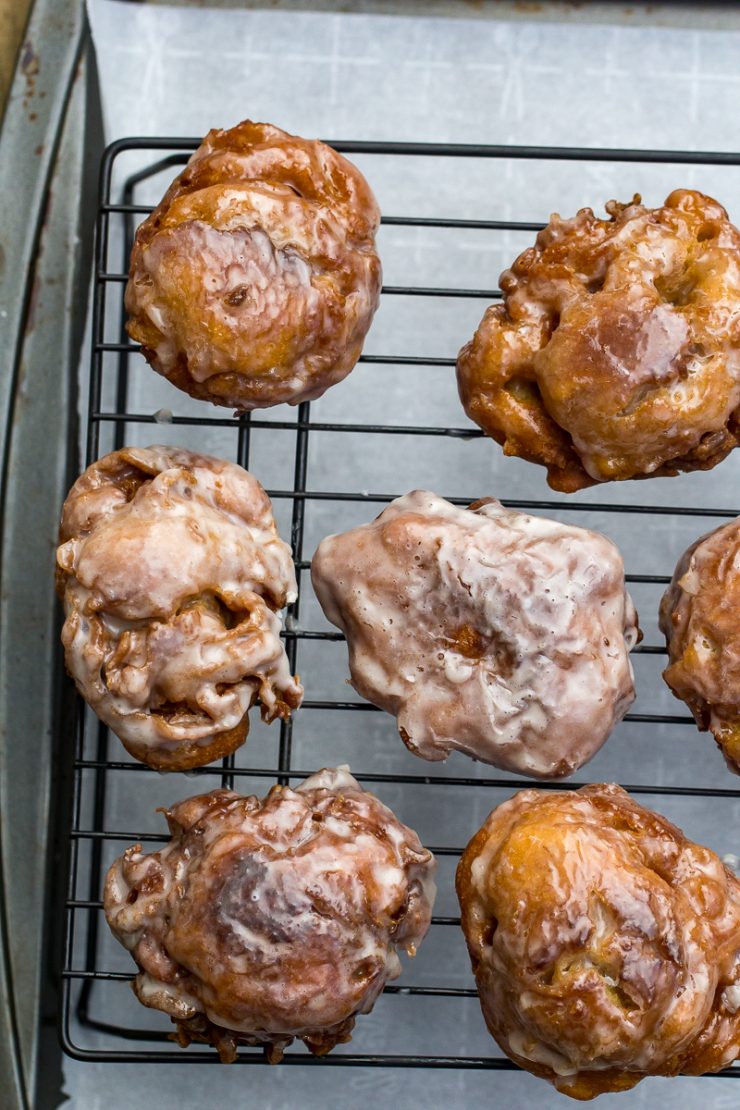 six apple fritters on a wire rack