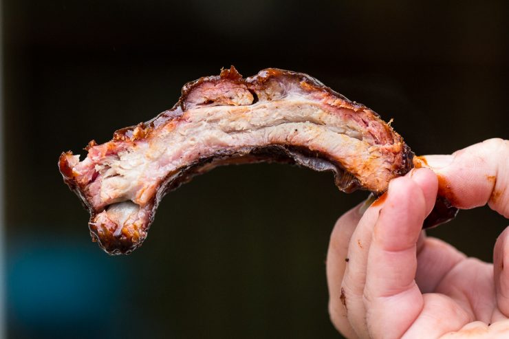 one bone of ribs being held up to see the smoke ring around the outside