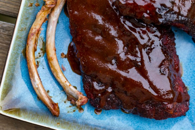 Two eaten bones of Smoked Cherry Coke Ribs on a blue plate