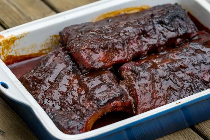 Smoked Cherry Coke Ribs in an enameled cast iron rectangle-shaped pan