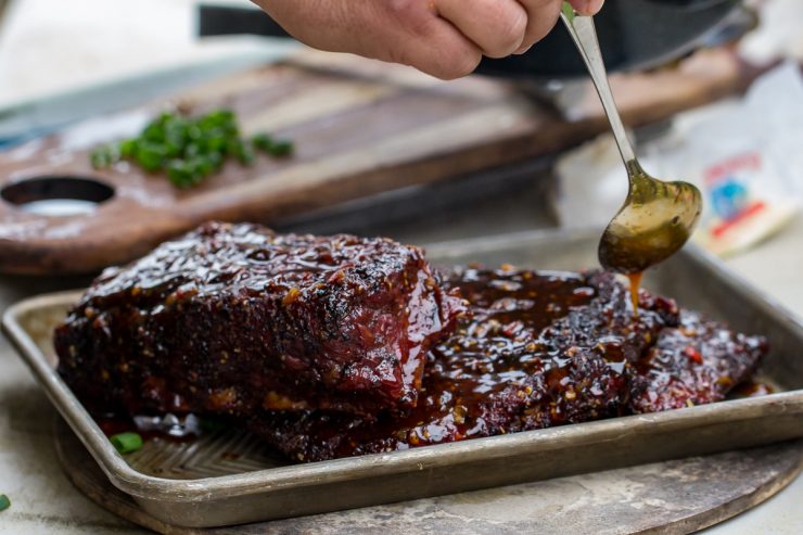 Spicy Asian Pork Ribs with sauce being poured over the top using a spoon