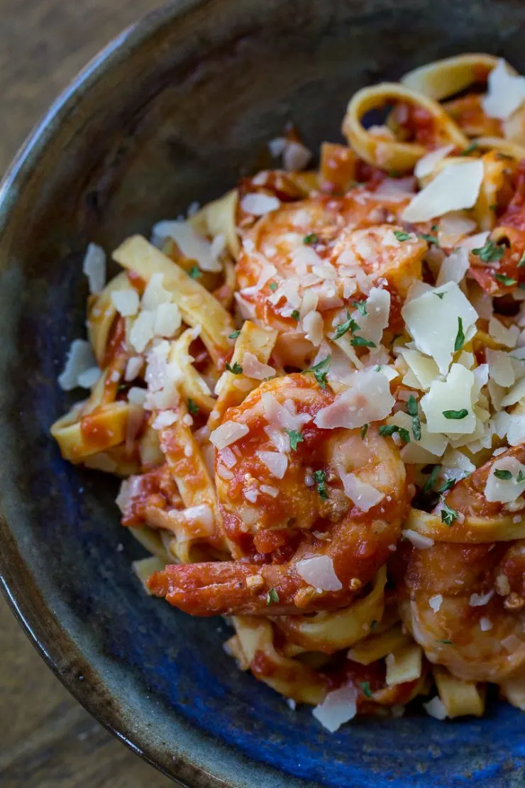 Shrimp Marinara in a blue and brown bowl with parmesan