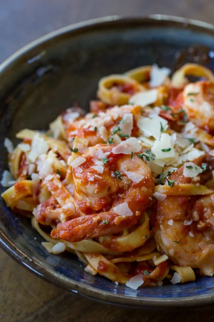 Shrimp Marinara in a blue bowl with parmesan cheese and parsley on top