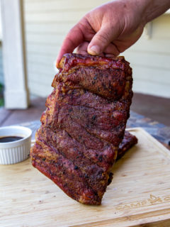 Rack of St. Louis ribs being held up vertically to camera