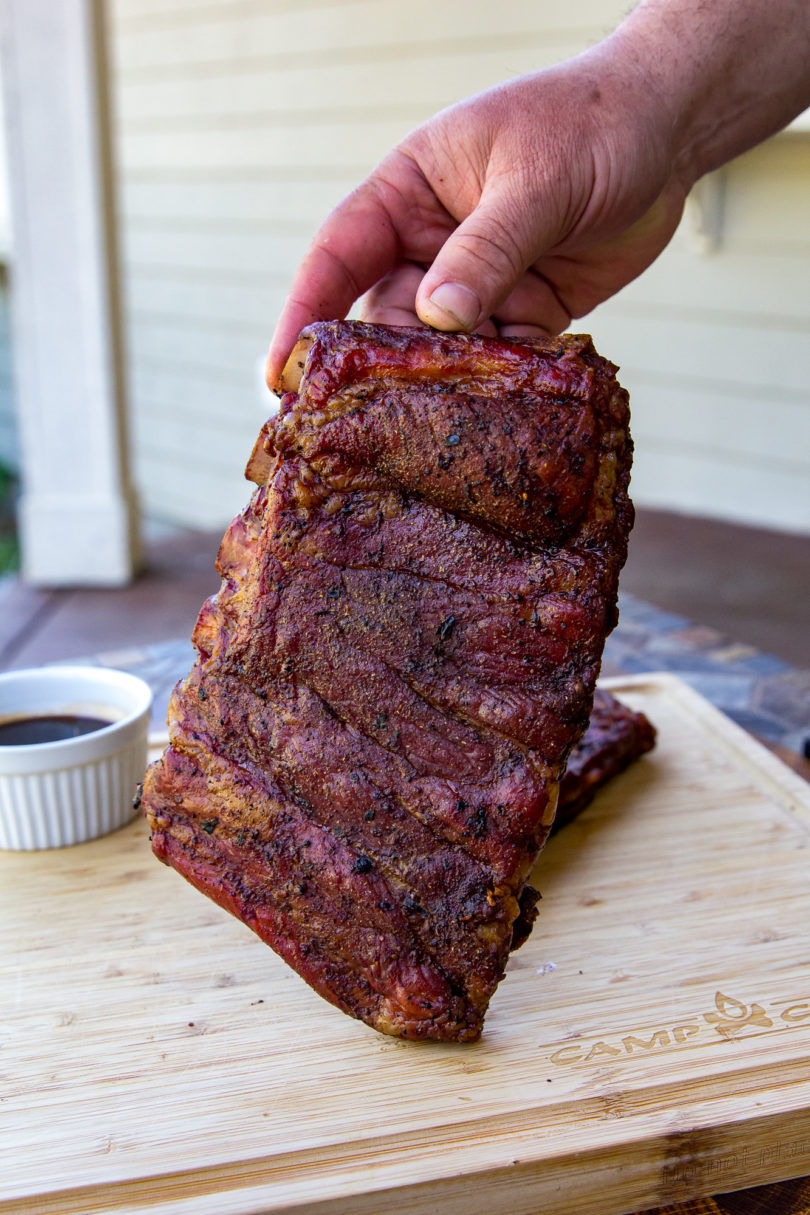 Rack of St. Louis ribs being held up vertically to camera