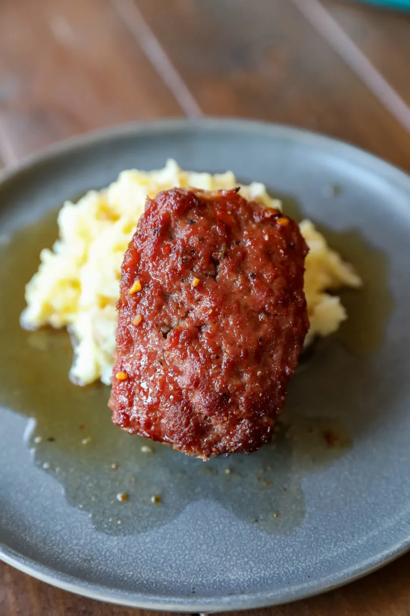 Smoked Meatloaf on a plate perched on some mashed potatoes