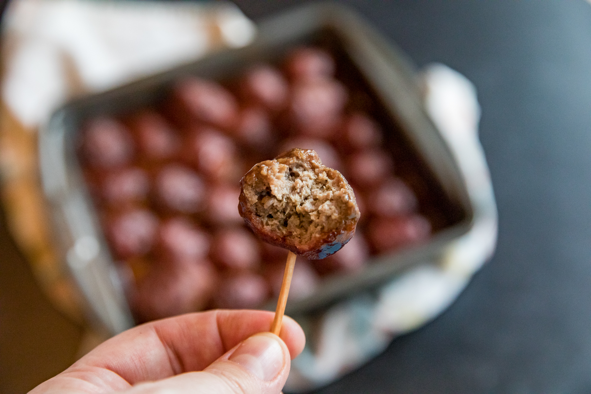 Traeger Grape Jelly Meatballs on a toothpick with a bite taken out
