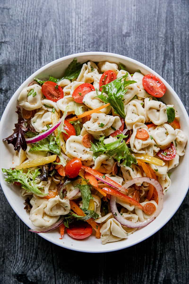 Colorful tortellini pasta salad with cherry tomatoes and fresh greens.