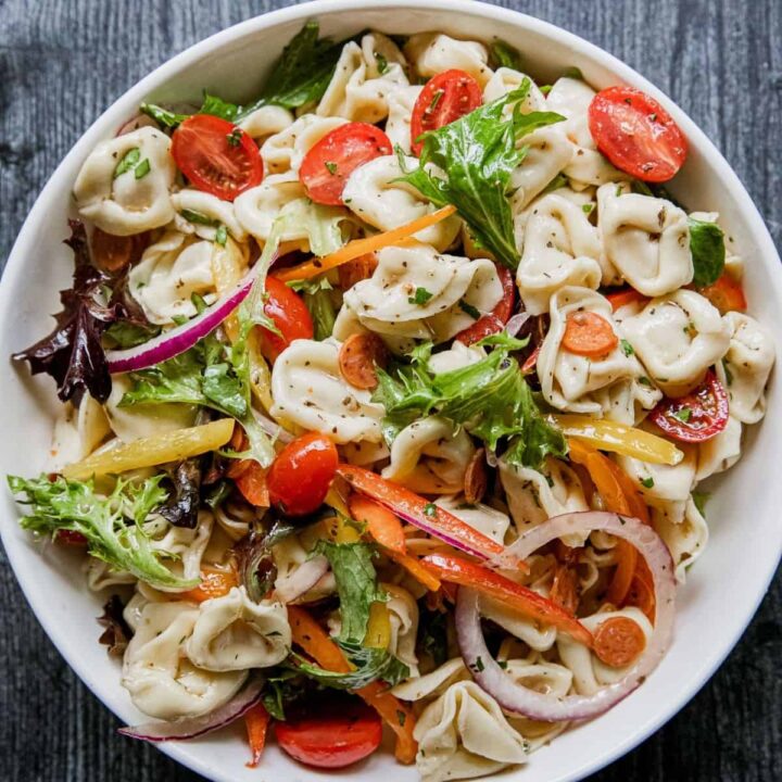 Colorful tortellini pasta salad with cherry tomatoes and fresh greens.