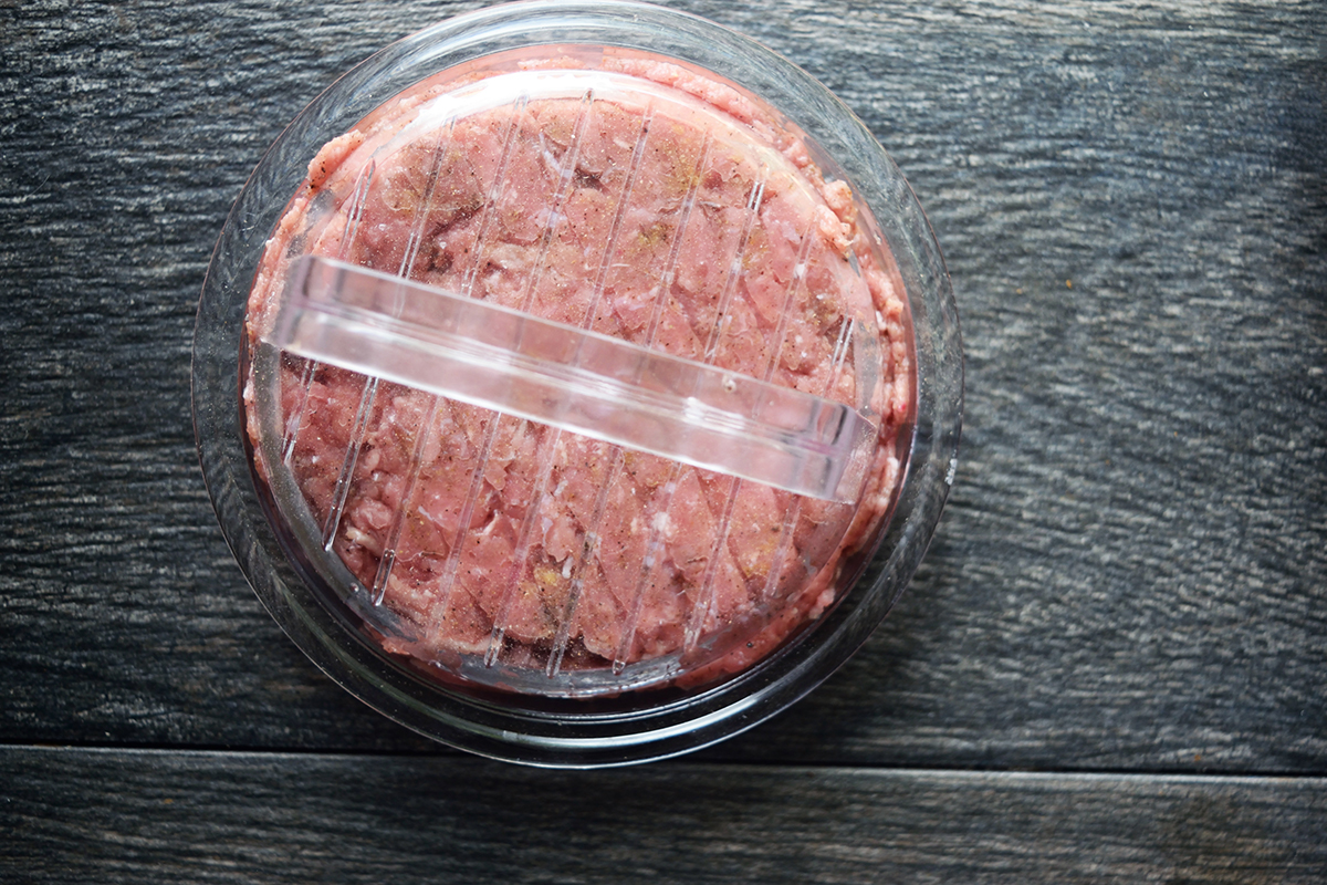 Air-fried turkey burgers served in a plastic container on a wooden table.