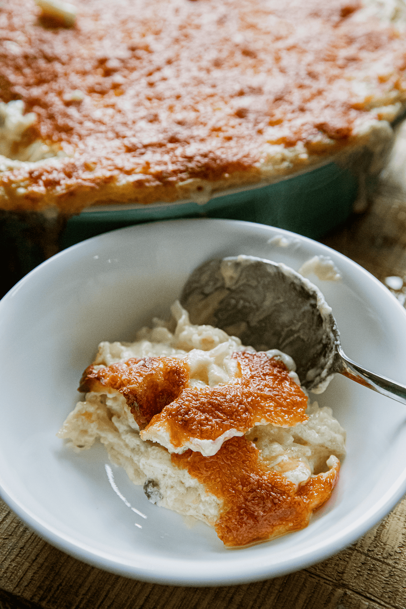 Delicious cheesy chicken casserole served in a white bowl with a spoon.