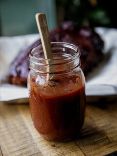 Honey BBQ Sauce in a mason jar with a wooden spoon in it.