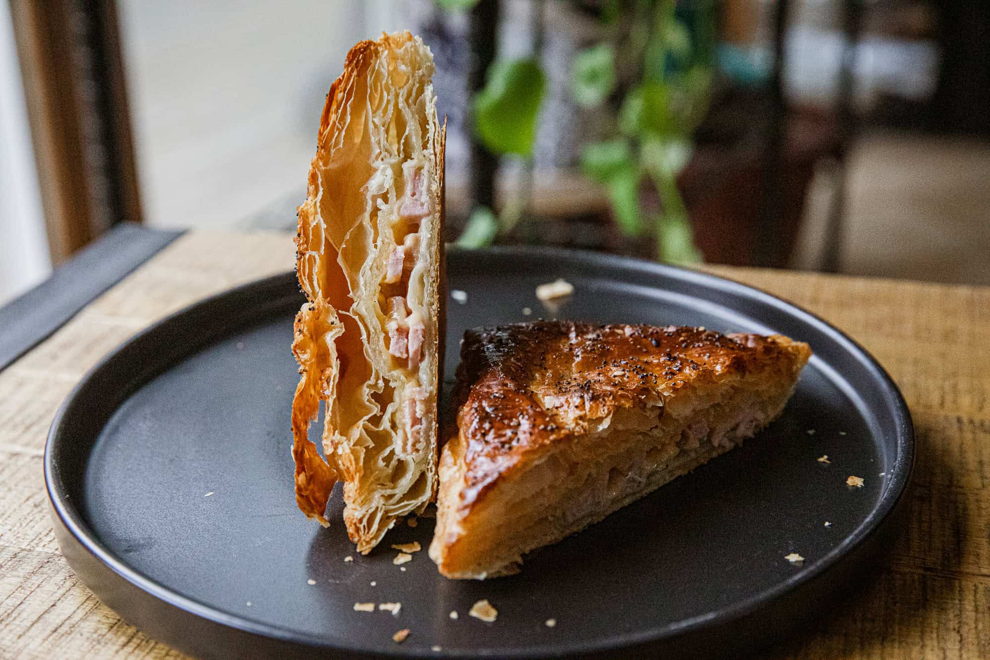 Crispy ham and cheese hot pocket on black plate, ready to eat.