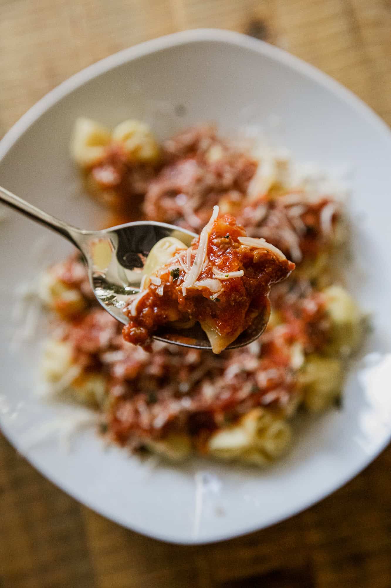 Tortellini pasta with rich meat sauce on a white plate. Perfect comfort food for pasta lovers.