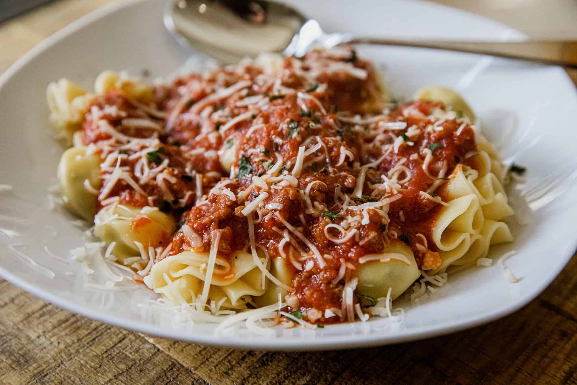 Delicious cheese tortellini topped with hearty meat sauce and sprinkled with grated cheese. Perfect.