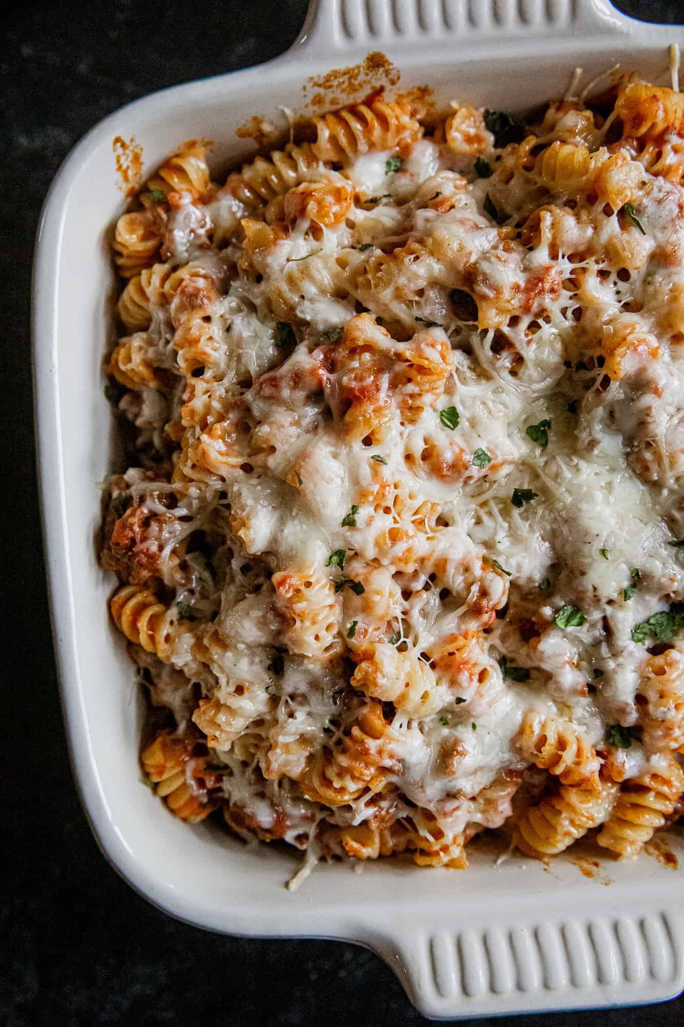 Cheesy Rotini Bake with melted cheese, pasta, and herbs in a baking dish. Perfect comfort food for f.