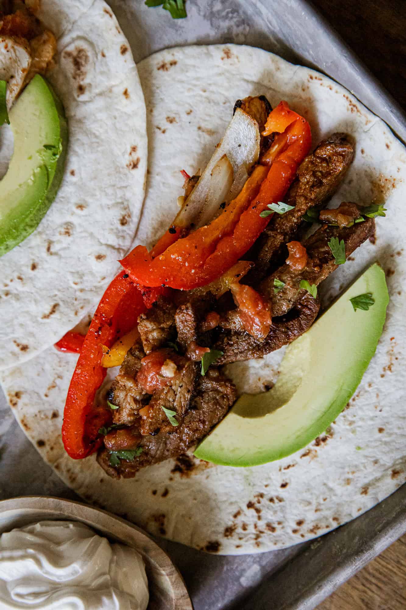 Steak fajitas with peppers and avocado on a soft tortilla, perfect for a flavorful meal.