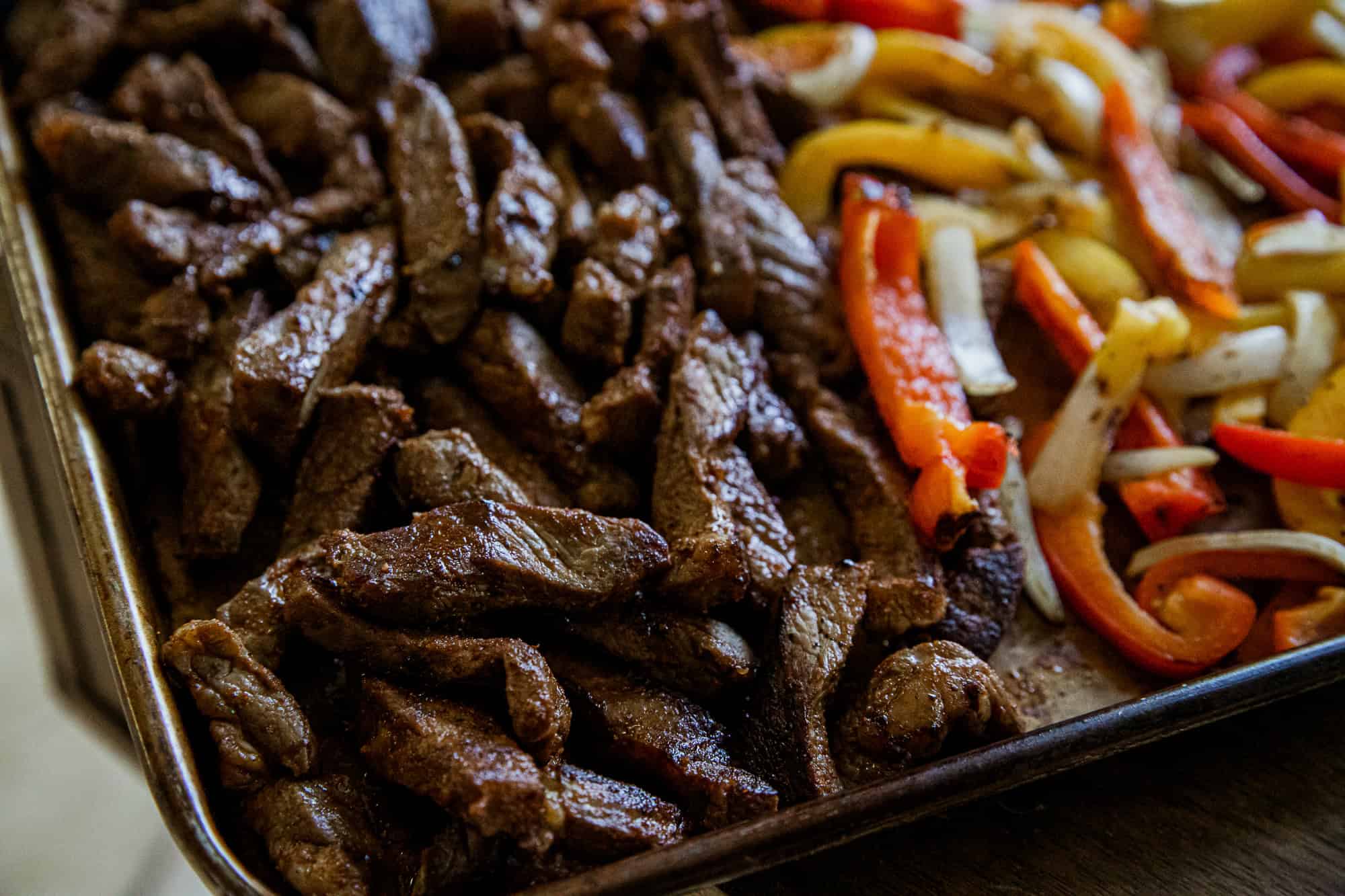 Juicy sliced steak with colorful bell peppers for fajitas.