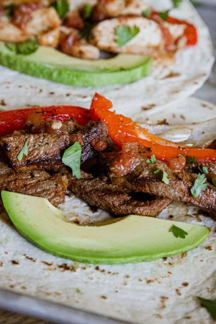 Steak fajitas with peppers and avocado on a soft tortilla, perfect for quick and flavorful meals.