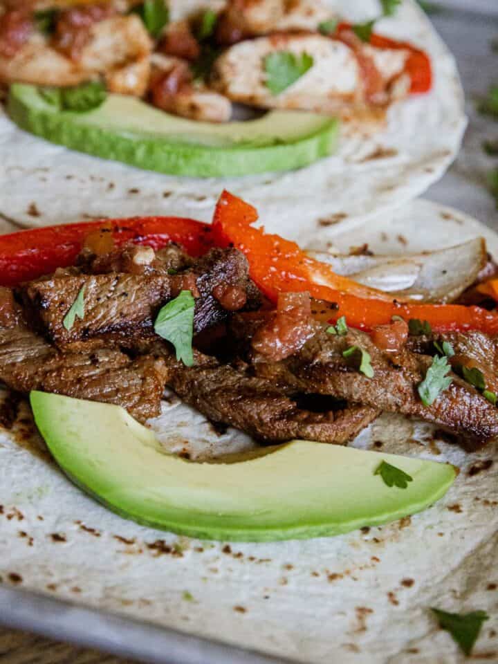 Steak fajitas with peppers and avocado on a soft tortilla, perfect for quick and flavorful meals.