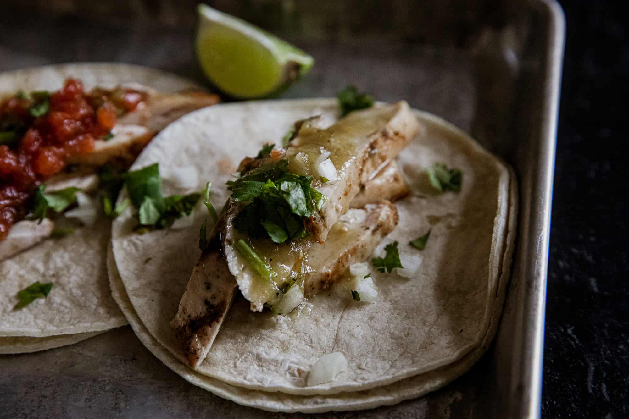 Delicious green chicken tacos with fresh cilantro and lime wedge. Perfect for a flavorful, healthy m.