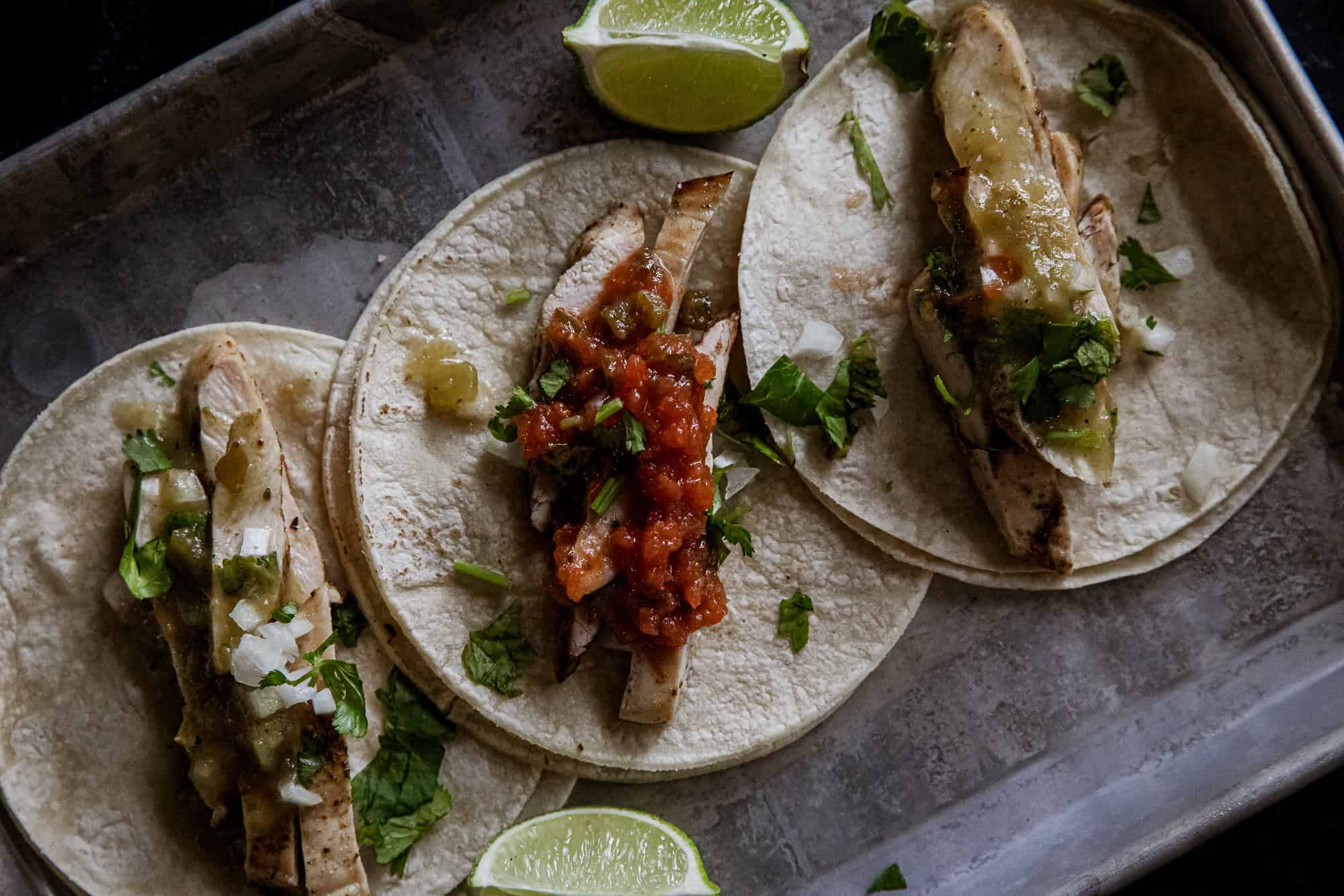 Delicious grilled chicken tacos with verde sauce and fresh herbs on soft tortillas.