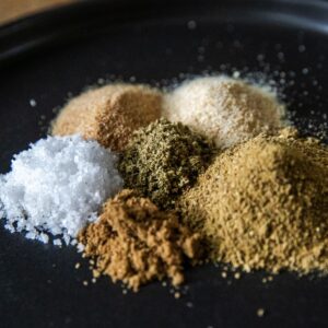 Assorted spices for Mexican Verde Rub on black background.