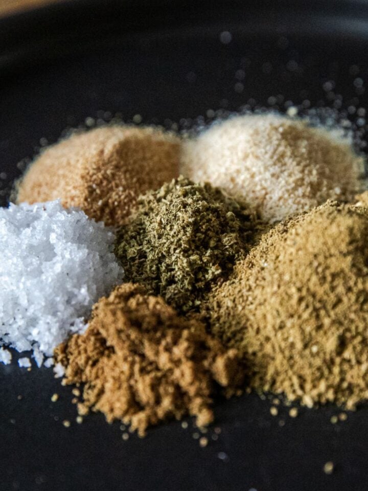 Assorted spices for Mexican Verde Rub on black background.