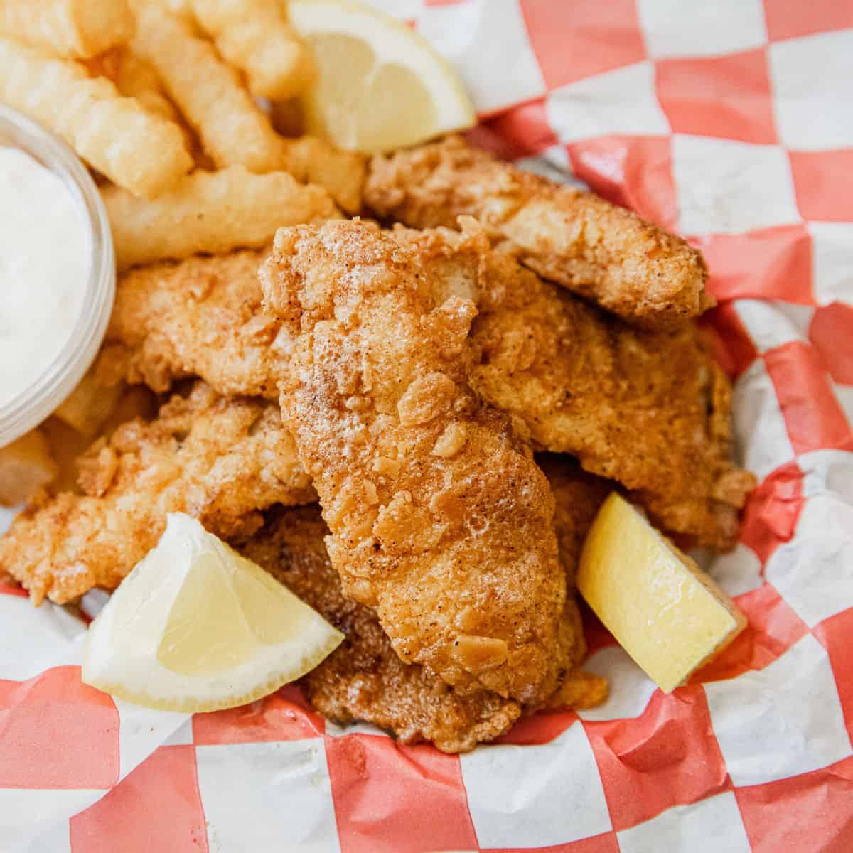 Golden crispy fried fish fillets served with lemon wedges and side of tartar sauce.