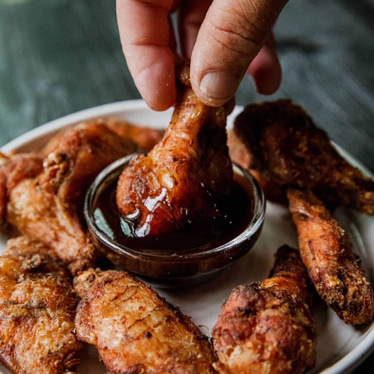 Juicy chicken wings dipped in barbecue sauce, served on a white plate.