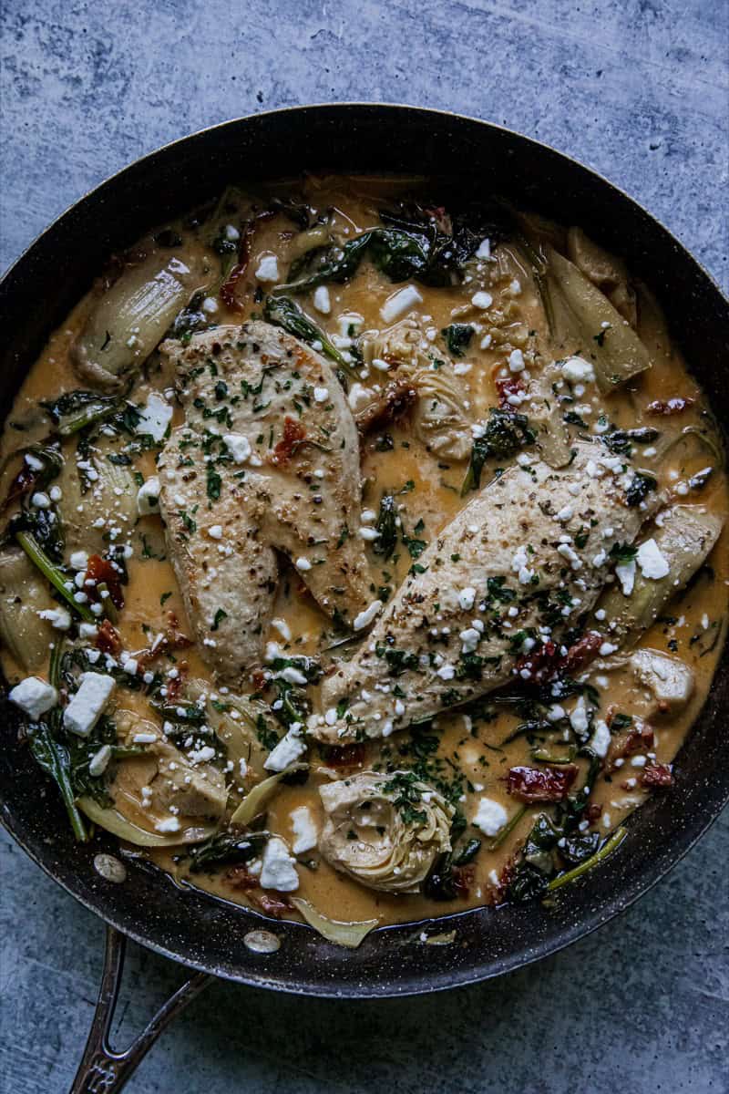 Creamy chicken and pasta skillet with herbs and cheese in a black skillet.