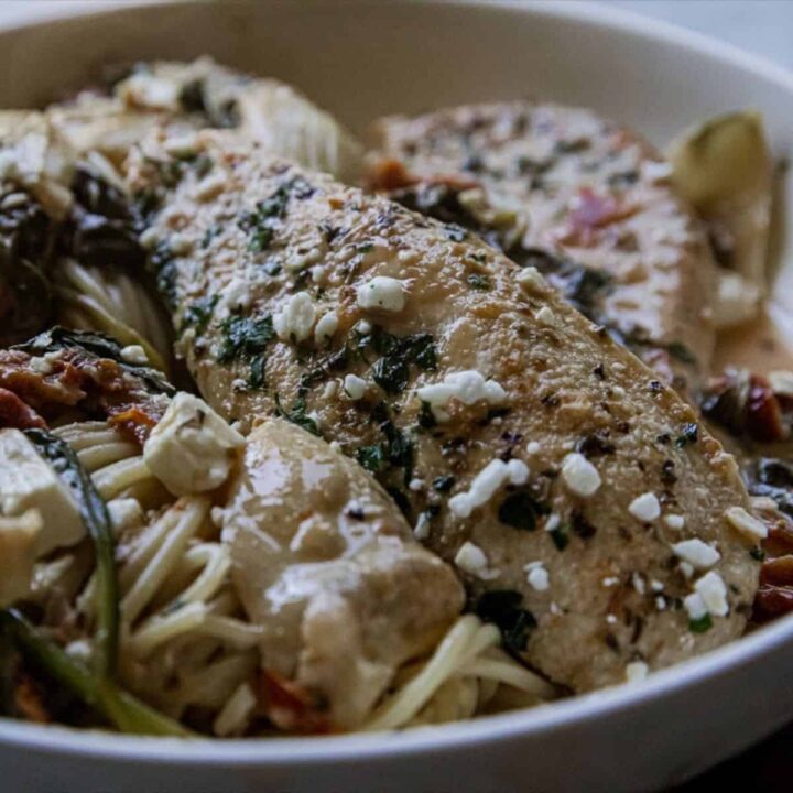 Delicious grilled fish served with vegetables and pasta in a white bowl.