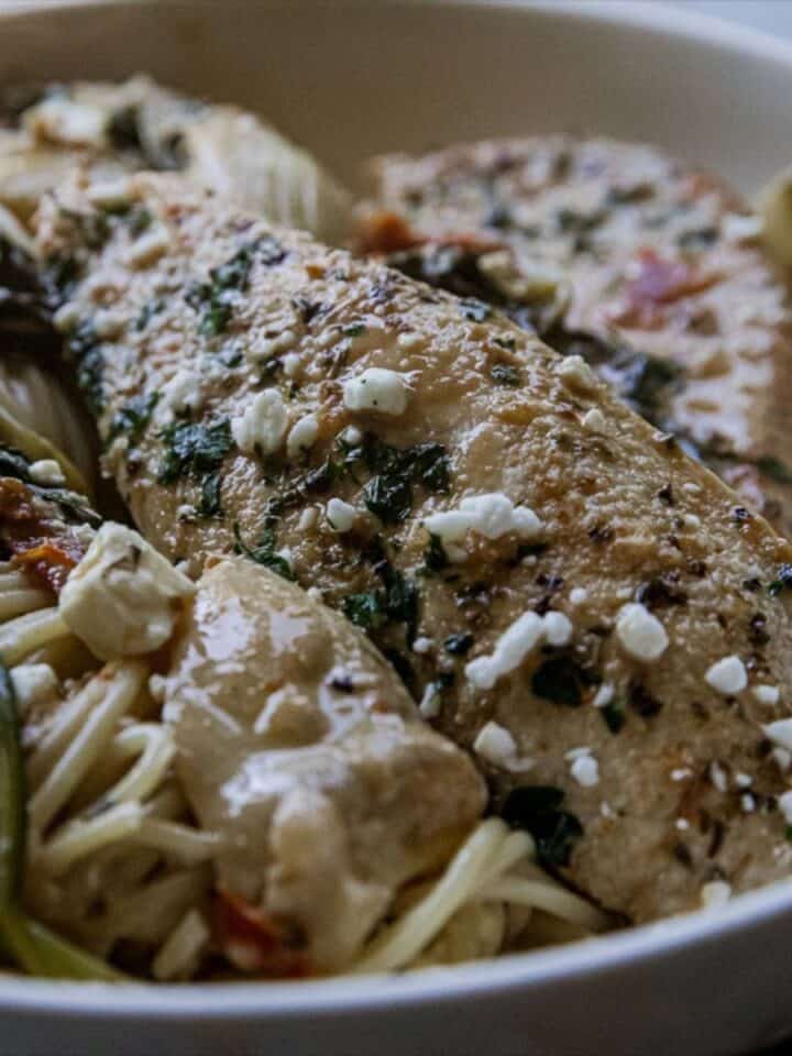 Delicious grilled fish served with vegetables and pasta in a white bowl.