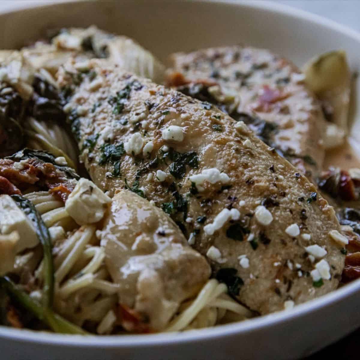 Delicious grilled fish served with vegetables and pasta in a white bowl.
