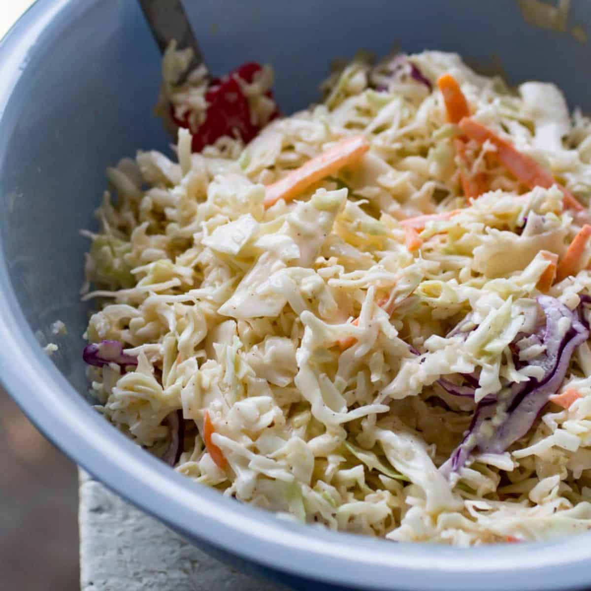 Fresh homemade coleslaw salad with shredded cabbage and carrots in a blue bowl.